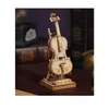 A miniature wooden cello model is displayed on a wooden stand, with books and a dark background in the blurred background. Anteprima dell’immagine prodotto