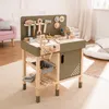 A wooden toy workbench with various tools and accessories is set up in a child's room, with a pink armchair and a large floor cushion visible in the background. Náhled obrázku produktu