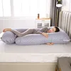 A woman is sleeping on a large U-shaped pillow in a bedroom. Náhled obrázku produktu