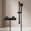 A black thermostatic bath mixer and a black shower set mounted on a tiled wall above a bathtub. Náhled obrázku produktu