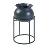 A dark gray planter pot with a ruffled rim sits on a dark gray metal stand. The background is white. Produktbild-Vorschau