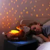 A child sleeping in bed next to a stuffed animal that projects stars onto the wall. Produktbild-Vorschau