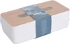 A tissue box with a wooden lid and a white base, wrapped in plastic packaging with a blue label. Produktbild-Vorschau