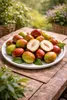 A plate of jujube fruits on a wooden table outdoors, with greenery in the background. Podgląd zdjęcia produktu