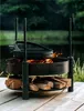 A fire pit with cooking accessories and firewood next to a lake. Náhled obrázku produktu