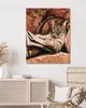 A diamond painting of a cat wearing glasses and reading a book is displayed on a wall above a cabinet and next to a chair. Produktbild-Vorschau