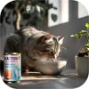 A cat eating from a bowl next to a can of cat food and a plant. Produktbild-Vorschau