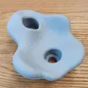 A light blue climbing hold with two holes is placed on a wooden surface. Voir les images du produit