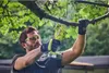 A man is using a Ryobi electric pruning saw to cut a tree branch outdoors. Podgląd zdjęcia produktu