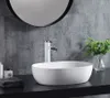A white oval vessel sink with a white faucet on a black countertop, with a gray tiled wall and a round mirror in the background. Anteprima dell’immagine prodotto