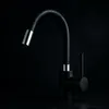 A black kitchen faucet with a flexible spout and a single lever handle, set against a dark background. Náhľad obrázku produktu