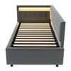 A dark gray upholstered bed frame with a slatted mattress base and integrated LED lighting at the headboard, shown from a side angle against a white background. Voir les images du produit