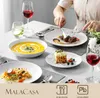 A table setting with porcelain dinnerware, food, and drinks, with a person's hands visible preparing to eat. Produktbild-Vorschau