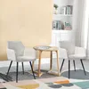 Two beige cord fabric chairs with black legs are placed around a small wooden table in a room with a cream-colored wall and a patterned rug. Náhled obrázku produktu