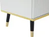 Close-up view of the bottom part of a white cabinet with gold trim and black legs with gold feet. Podgląd zdjęcia produktu