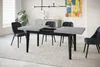 A modern dining room with a light-colored rug, a gray and black extendable dining table, and dark gray chairs. Produktbild-Vorschau
