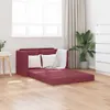 A red sofa bed with white pillows and a white blanket is shown in a room with wooden floors, a window with blinds, and a plant. Produktbild-Vorschau