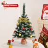 A small, decorated Christmas tree on a table, with Christmas stockings and a picture of Santa Claus in the background. Anteprima dell’immagine prodotto