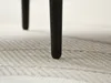 Close-up view of the black legs of a table resting on a textured rug. Produktbild-Vorschau