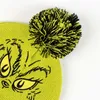 Close-up of a green knitted hat with a black and yellow pom-pom and a Grinch face embroidered on it. Podgląd zdjęcia produktu
