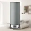 A cylindrical table lamp with a gray fabric shade and a silver base, shown in a room with a blurred background. Dimensions are indicated with text overlays. Produktbild-Vorschau