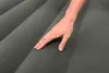A hand is touching a gray inflatable mattress. Náhled obrázku produktu