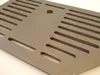 A close-up, angled view of a gray metal grate with multiple slots and a circular hole. Anteprima dell’immagine prodotto