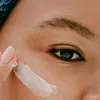 A close-up shot of a person applying eye cream. Podgląd zdjęcia produktu