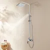 A modern silver shower system with a square overhead showerhead and a handheld showerhead, both spraying water, set against a light beige and white background with soft shadows. Náhled obrázku produktu