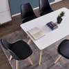 A dining set with black chairs and a white table, with books and a plant on the table. Voir les images du produit