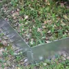 Metal garden edging is installed in a natural outdoor setting with grass, leaves, and dirt. Produktbild-Vorschau