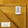 A close-up view of a yellow towel with care labels attached. Produktbild-Vorschau