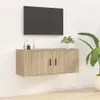 A wall-mounted TV cabinet with a television mounted above it, and a plant to the right. Voir les images du produit