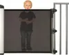 A young child is standing behind a black mesh safety gate. Náhľad obrázku produktu