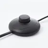 A close-up shot of a black floor lamp foot switch on a white background. Anteprima dell’immagine prodotto
