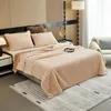 A neatly made bed with a plush blanket and pillows, set in a bedroom with a floor lamp and a chair in the background. Produktbild-Vorschau