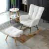 A white rocking chair and ottoman are placed on a patterned rug in a room with a small side table and a bookshelf in the background. Podgląd zdjęcia produktu
