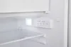 Close-up of the interior of a white refrigerator, showing a shelf, a light, and the control panel. Produktbild-Vorschau
