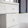 Close-up of white drawers with clear knobs. Produktbild-Vorschau