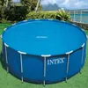 An Intex solar pool cover is shown on a round above-ground pool, set up on a grassy lawn with a tropical background. Voir les images du produit