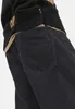 A close-up shot of the back pocket of a pair of black jeans, worn by a person. Produktbild-Vorschau