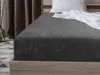 A close-up view of a dark gray fitted sheet on a bed. Náhled obrázku produktu