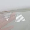 A close-up view of a sheer white curtain with silver triangular patterns, showing a hand underneath. Produktbild-Vorschau
