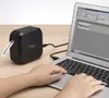 A person's hands are typing on a laptop, which is connected to a black label printer. A label with the word "Welcome!" is being printed. Náhled obrázku produktu