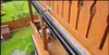 A close-up view of a balcony railing and gutter system, with a garden visible in the background. Produktbild-Vorschau