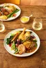 A close-up of a plate of food with roasted chicken and vegetables, served on a wooden table with a glass of white wine and a small dish of mustard. Anteprima dell’immagine prodotto