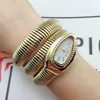 A woman's wrist wearing a gold snake-shaped watch. Podgląd zdjęcia produktu