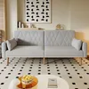 A light gray sofa with diamond-stitched upholstery and wooden legs is shown in a living room setting. Voir les images du produit