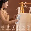 A woman is steaming a dress with a handheld garment steamer. Podgląd zdjęcia produktu