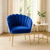 A blue velvet armchair with gold legs sits next to a small round side table with a marble top and gold legs. A vase with greenery and a small golden bowl are on the table. The scene is set in a room with light-colored curtains and a neutral rug. Produktbild-Vorschau